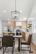 Kitchen featuring pendant lighting, sink, appliances with stainless steel finishes, light brown cabinetry, and light wood-type flooring