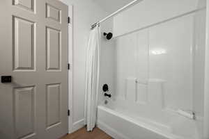 Bathroom with shower / bathtub combination with curtain and hardwood / wood-style flooring