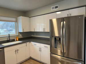 Kitchen with white cabinetry, sink, and appliances with stainless steel finishes