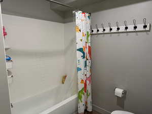 Bathroom with shower / bath combination with curtain and toilet