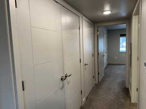 Hallway with a textured ceiling and dark carpet