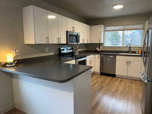 Kitchen featuring white cabinetry, sink, stainless steel appliances, and kitchen peninsula