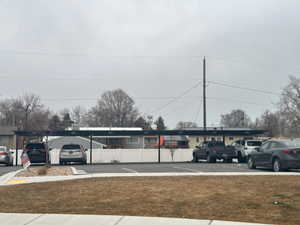 View of vehicle parking with a carport and a lawn