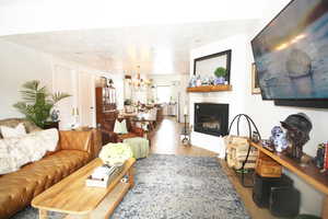 Living room featuring a textured ceiling,  wood-tile flooring, and an inviting chandelier