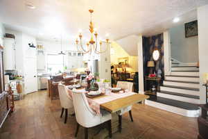 Dining area with a textured ceiling, an inviting chandelier, and wood-tile flooring