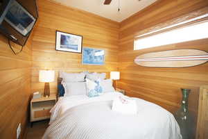 Bedroom featuring ceiling fan and wooden walls