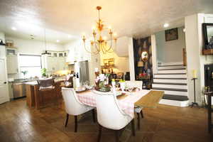 Dining room with a textured ceiling, dark wood-tile flooring, and a chandelier