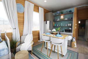 Kitchen featuring light wood-type flooring, refrigerator, a kitchen breakfast bar, and backsplash