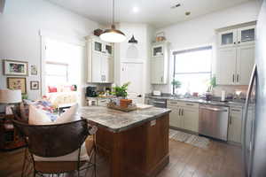 Kitchen featuring sink, pendant lighting, dark wood-tile flooring, stainless steel dishwasher, and light stone countertops