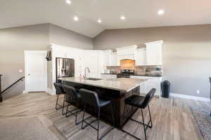 Kitchen featuring white cabinetry, a kitchen bar, a large island with sink, and appliances with stainless steel finishes