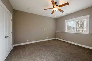 Unfurnished bedroom featuring dark carpet and ceiling fan