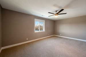 Carpeted empty room featuring a textured ceiling and ceiling fan