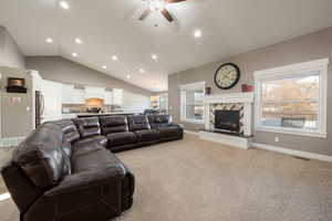 Living room featuring lofted ceiling, light carpet, and ceiling fan