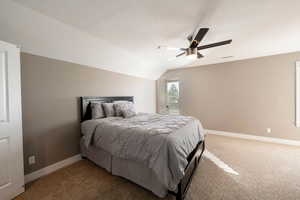 Bedroom with ceiling fan, lofted ceiling, carpet floors, and a textured ceiling