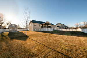 Back of house with a lawn and a storage unit