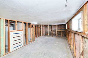 Basement with water heater, gas water heater, and a textured ceiling