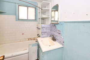 Bathroom with tile walls, a bath, and vanity