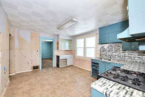 Kitchen with sink, black gas stove, and blue cabinets