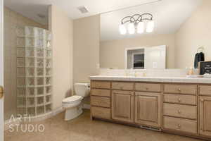 Bathroom with tile patterned floors, toilet, vanity, and a tile shower