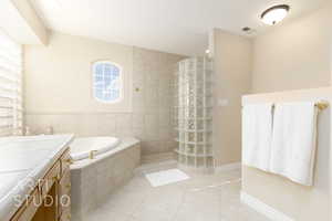 Bathroom featuring vanity, tile patterned flooring, and shower with separate bathtub