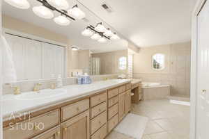 Bathroom with vanity, tile patterned flooring, and tiled tub