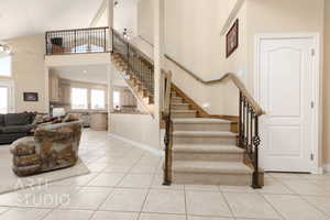 Stairs featuring a towering ceiling, tile patterned floors, and ceiling fan