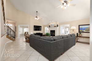 Tiled living room with ceiling fan, a tiled fireplace, and high vaulted ceiling