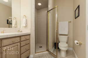 Bathroom featuring tile patterned flooring, vanity, an enclosed shower, and toilet