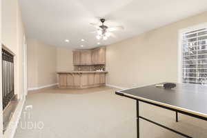 Kitchen with ceiling fan, light colored carpet, backsplash, and light brown cabinetry