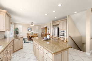 Kitchen with a breakfast bar area, a center island, light tile patterned floors, light stone counters, and stainless steel appliances