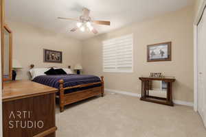 Bedroom with light colored carpet, ceiling fan, and a closet