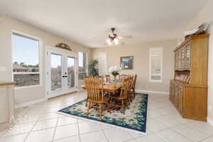 Tiled dining room with french doors and ceiling fan