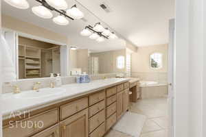 Bathroom featuring tiled tub, vanity, and tile patterned floors