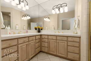 Bathroom featuring vanity, a shower with shower door, tile patterned flooring, and backsplash