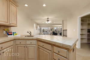 Kitchen with sink, tile counters, kitchen peninsula, and light brown cabinets