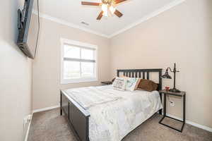 Carpeted bedroom with ornamental molding and ceiling fan