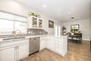 Kitchen with white cabinetry, light hardwood / wood-style flooring, kitchen peninsula, and dishwasher