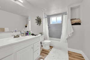 Full bathroom with toilet, vanity, wood-type flooring, and shower / bath combo with shower curtain