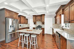 Kitchen with sink, appliances with stainless steel finishes, a kitchen island, and light stone countertops