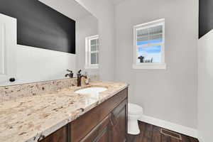 Bathroom featuring wood-type flooring, vanity, and toilet