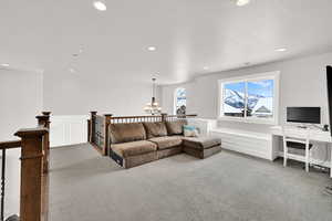 Living room featuring a textured ceiling, carpet flooring, and a notable chandelier