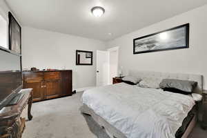 Bedroom with a textured ceiling and light colored carpet