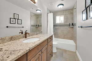 Full bathroom with a textured ceiling, toilet, vanity, and shower / bathtub combination with curtain