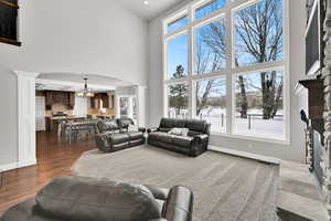 Living room featuring a fireplace, a towering ceiling, decorative columns, and dark hardwood / wood-style floors