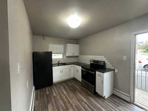 Unit 3 Kitchen with sink, white cabinetry, black refrigerator, a baseboard radiator, and electric stove