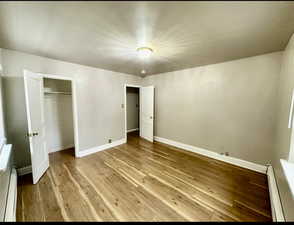 Unit 4 bedroom #2 with a baseboard radiator, light hardwood / wood-style floors, and a closet