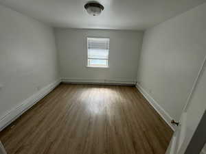 Unit 1 bedroom featuring a baseboard radiator and dark hardwood / wood-style floors