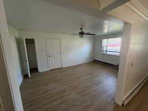 Unit 1 family room with wood-type flooring, a baseboard heating unit, two closets, and ceiling fan