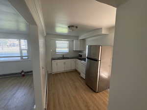 Unit 1 Kitchen featuring sink, white cabinetry, range, light hardwood / wood-style flooring, and stainless steel fridge