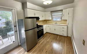 Unit 4 Kitchen featuring sink, light wood-type flooring, appliances with stainless steel finishes, white cabinets, and a baseboard heating unit